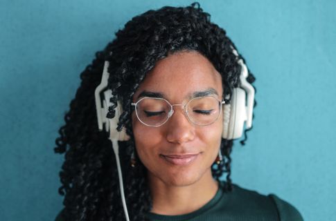 A photo of a woman with headphones listening with her eyes closed