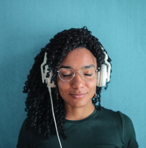 A photo of a woman with headphones listening with her eyes closed