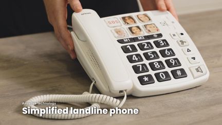 Hands holding an adaptive house phone with large numbers and picture dial buttons.