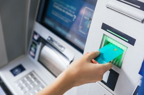 A hand inserting a card into an ATM.