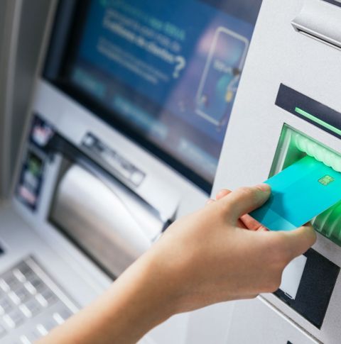 A hand inserting a card into an ATM.