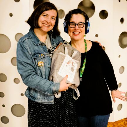 Two happy women standing together, one holding a sensory backpack