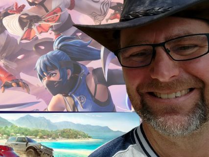 A man in a hat in front of a collage of stills from video games