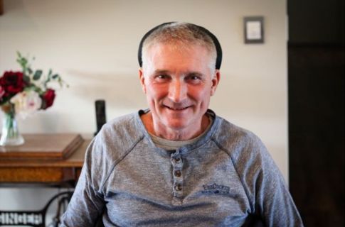 Gary sitting in his chair in living room smiling.