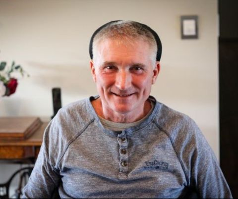 Gary sitting in his chair in living room smiling.