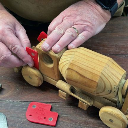 A man using shim gauges to measure a wooden toy