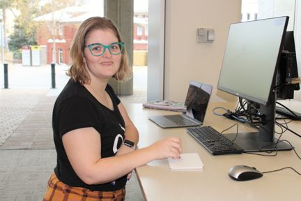 A young person looks as the camera while typing on a computer