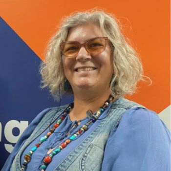 A tall woman with colourful jewellery smiles widely