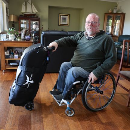 A man in a wheelchair holding an adapted luggage bag
