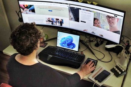 A woman sitting at a computer with a wide screen