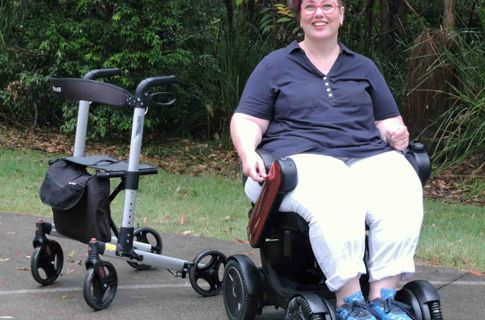 A smiling lady in a power wheelchair outside