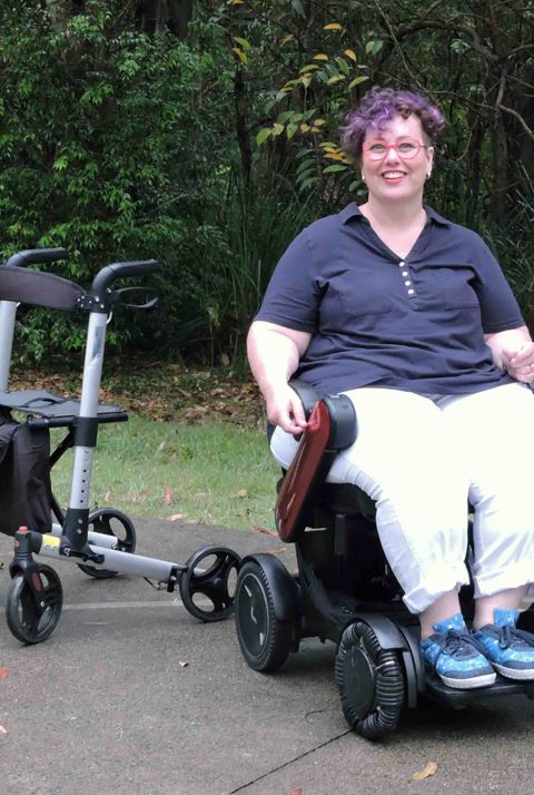 A smiling lady in a power wheelchair outside