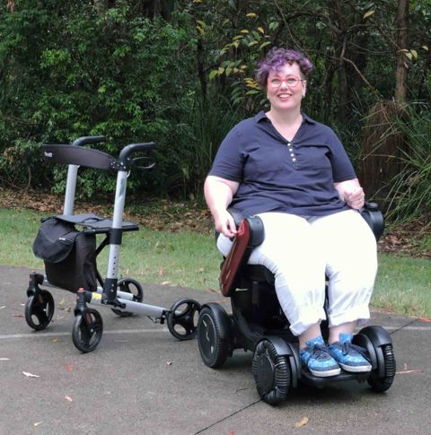 A smiling lady in a power wheelchair outside
