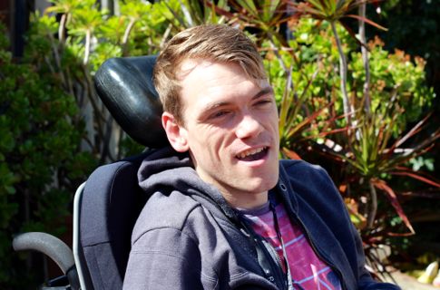 Peter outdoors on sunny day in wheelchair.