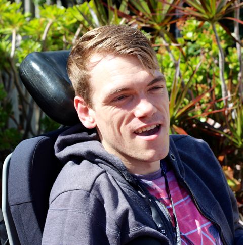 Peter outdoors on sunny day in wheelchair.