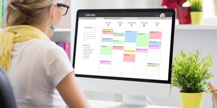 A photo of a woman looking at a computer screen with an electronic calendar