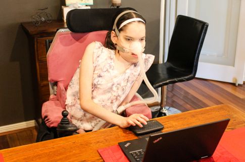 Rebecca sitting at office desk using laptop.