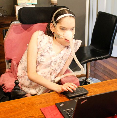 Rebecca sitting at office desk using laptop.