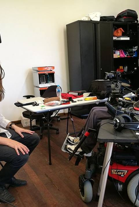 Two men in an audio studio, one of whom is in a power wheelchair