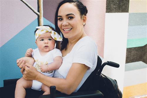 woman sits in wheelchair holding a baby
