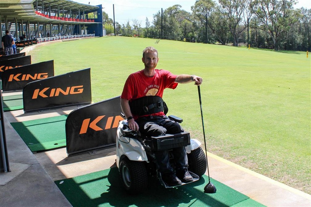 clint paragolfer man wearing red top holds golf club whilst sitting in paragolfer