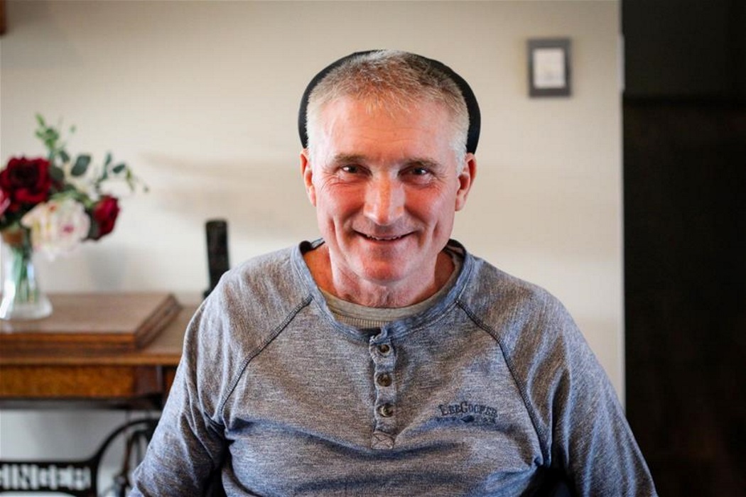 man wearing grey top sits in wheelchair