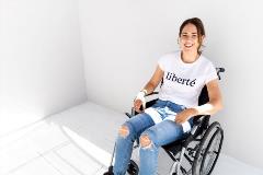 woman sits in a wheelchair and smiles at camera