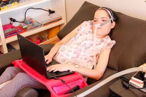 rebecca-5 woman reclines in armchair with laptop sitting on tray table over lap