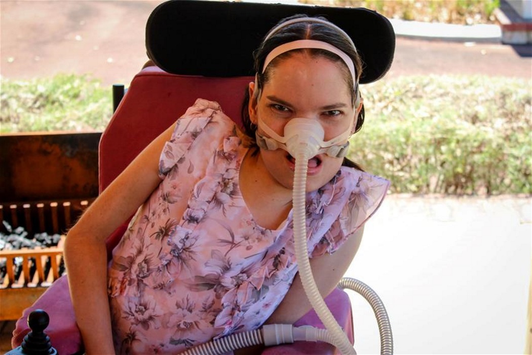 rebecca_reduce woman sitting in wheelchair wearing a breathing device