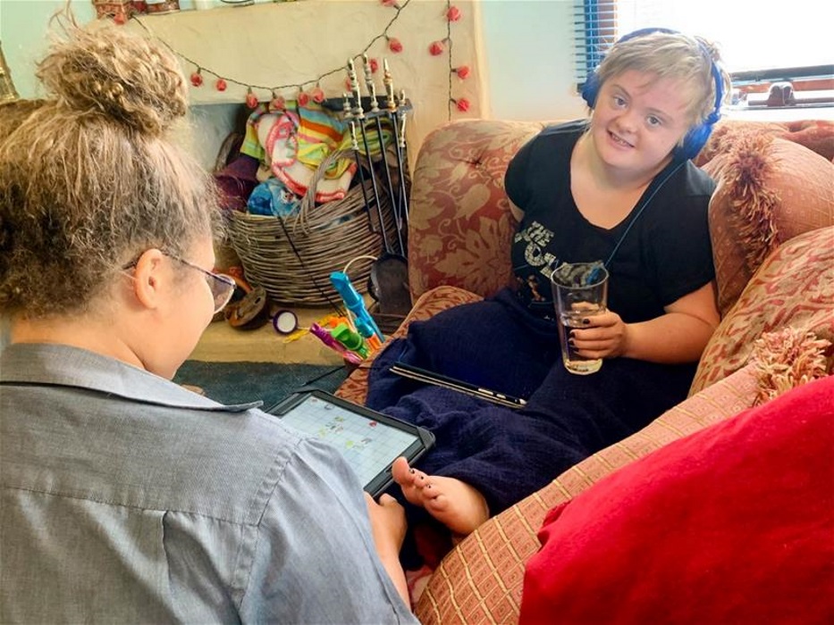 sophie_resize woman wearing headphones sits on couch across from woman with back to camera