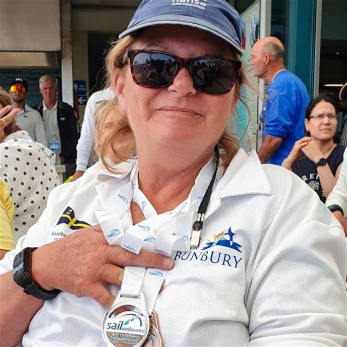 tracy_crop woman wearing blue cap and white polo holds up two medals