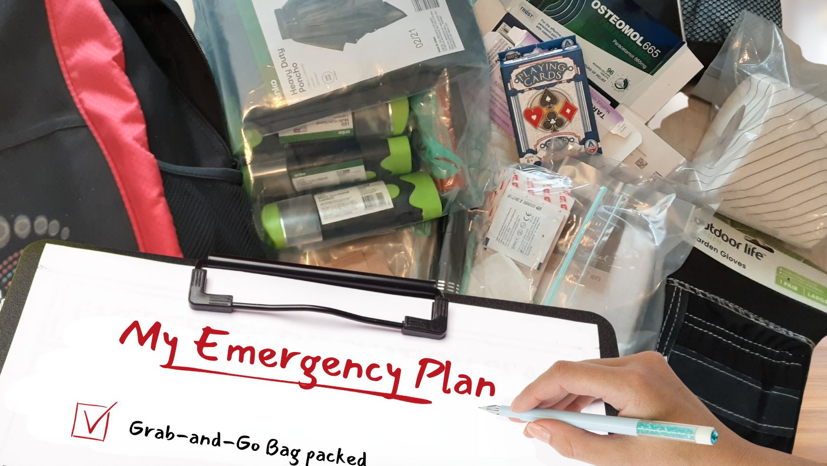 Grab-and-Go Bag packed Image shows a hand with a pen writing on a clipboard with the title, My emergency plan. There is a ticked box underneath beside the words; Grab-and-Go Bag packed. Behind the clipboard are the contents of the bag.