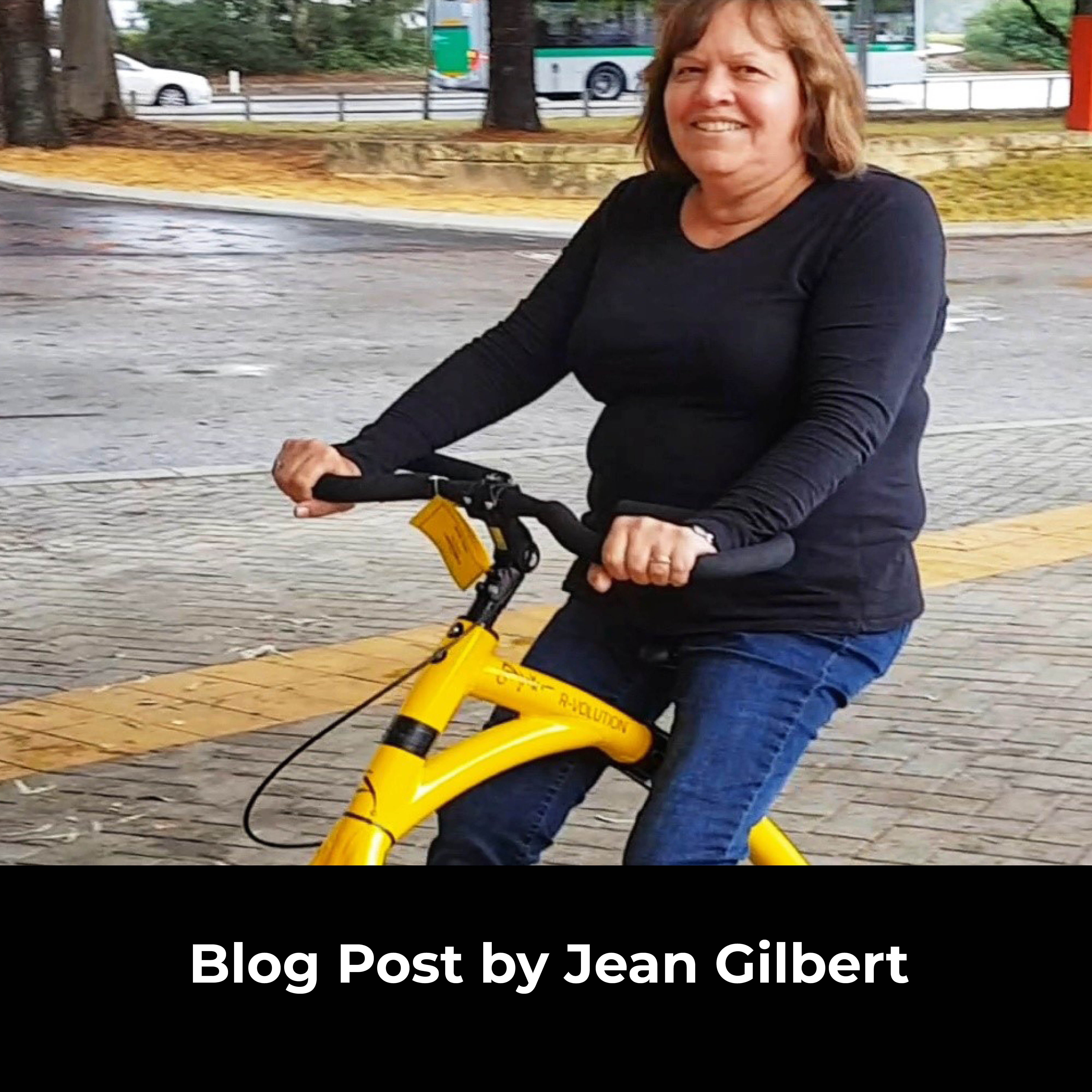 Woman seated on the Alinker walking bike outside. White text overlay on black background says, blog post by Jean Gilbert