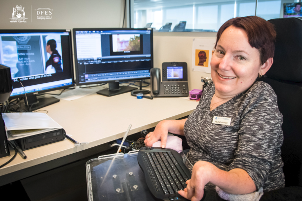 Melanie sits at her modified work station and smiles. Melanie sits at her modified work station and smiles.