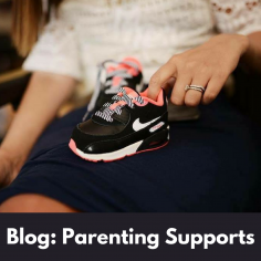 Image of a woman's lap with her finger on a child's pair of black Nike runners. White text on a black background says, blog: Parenting Supports