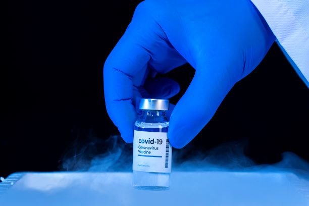 A gloved hand holds a bottle of Covid-19 vaccine