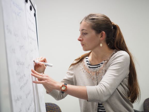 A lady stands at a board planning.