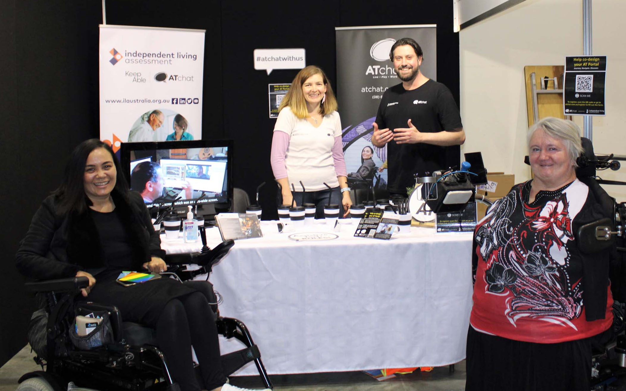 AT Chat at DAC with Danika and Neil A group of people stand by an AT Chat Expo stand and look at the camera.