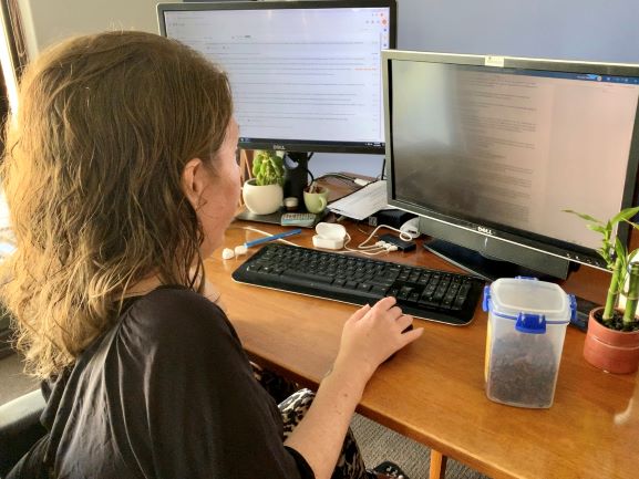 woman sits in front of two computer screens