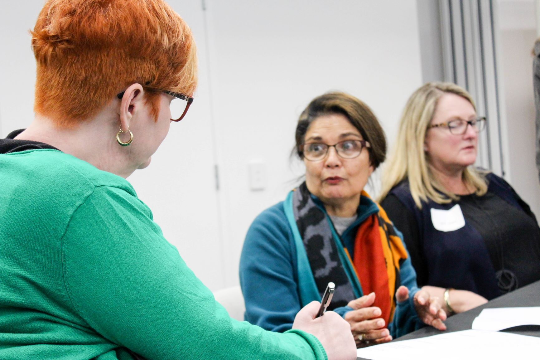 woman wearing green top talks to two women