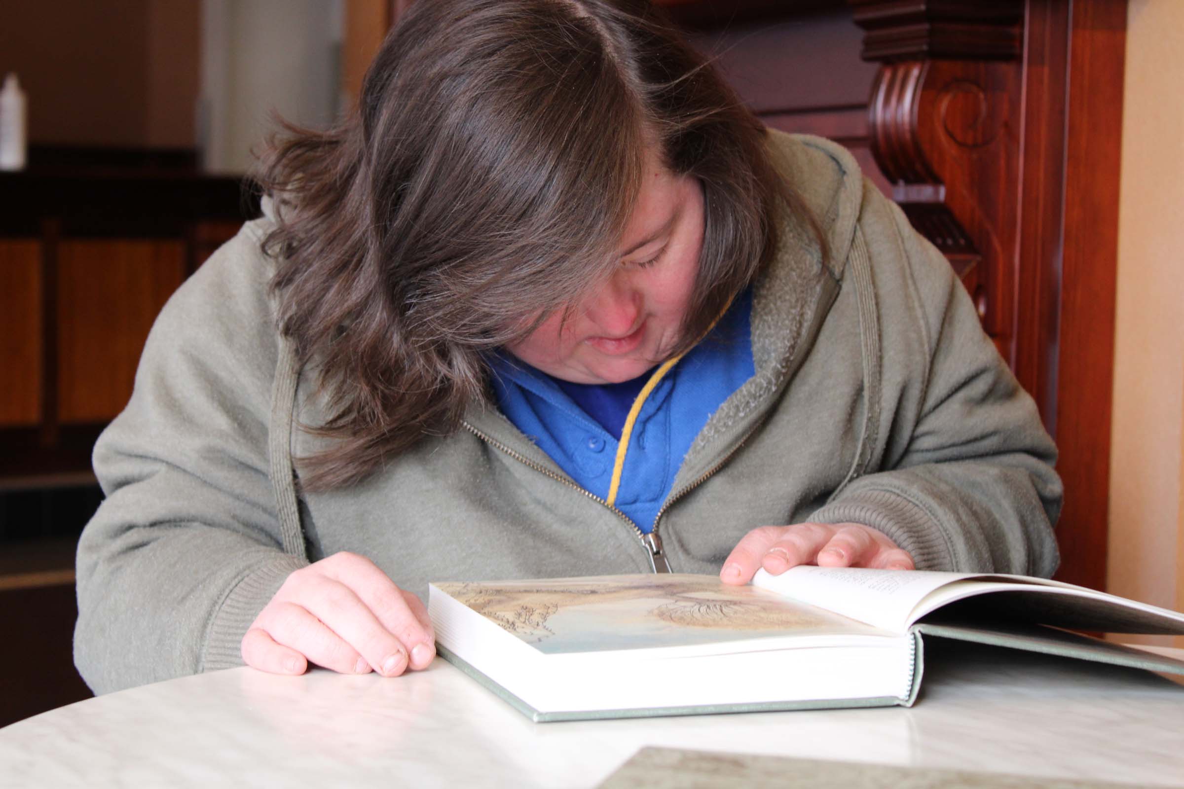 A woman reads a book at a table.