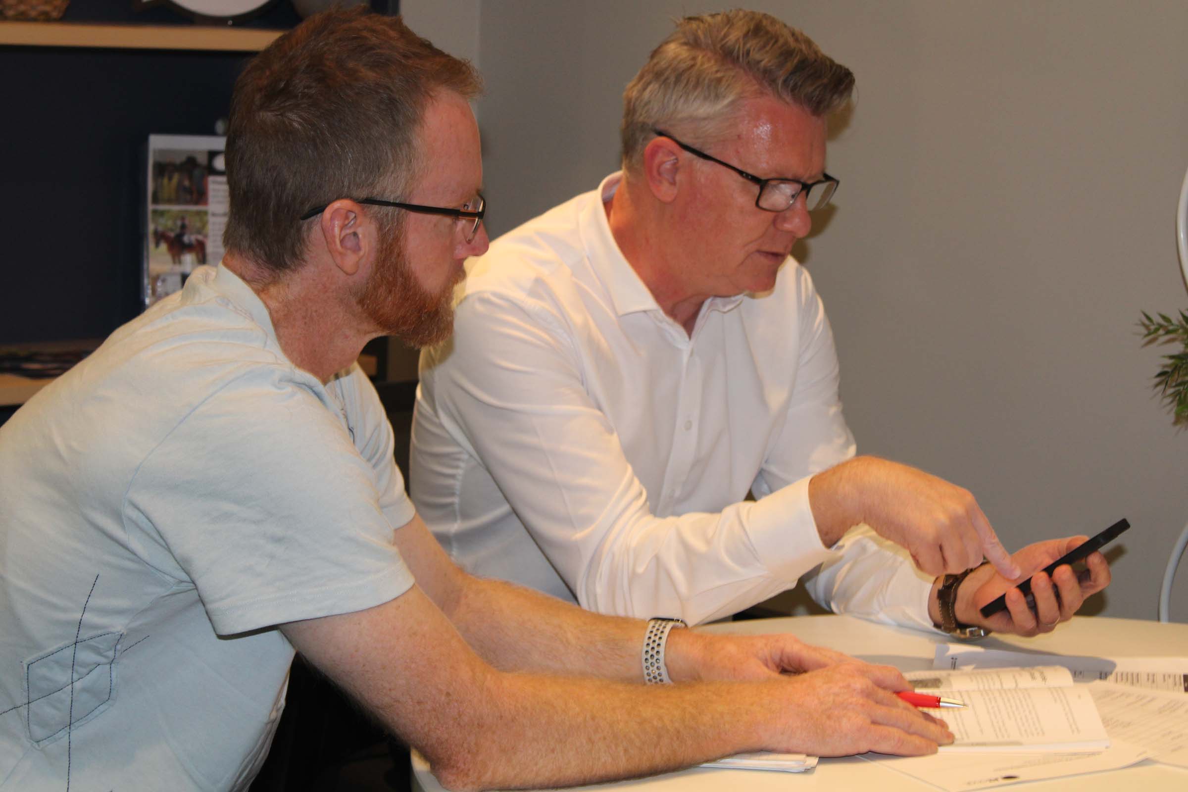 Two men sit at a table and work together.