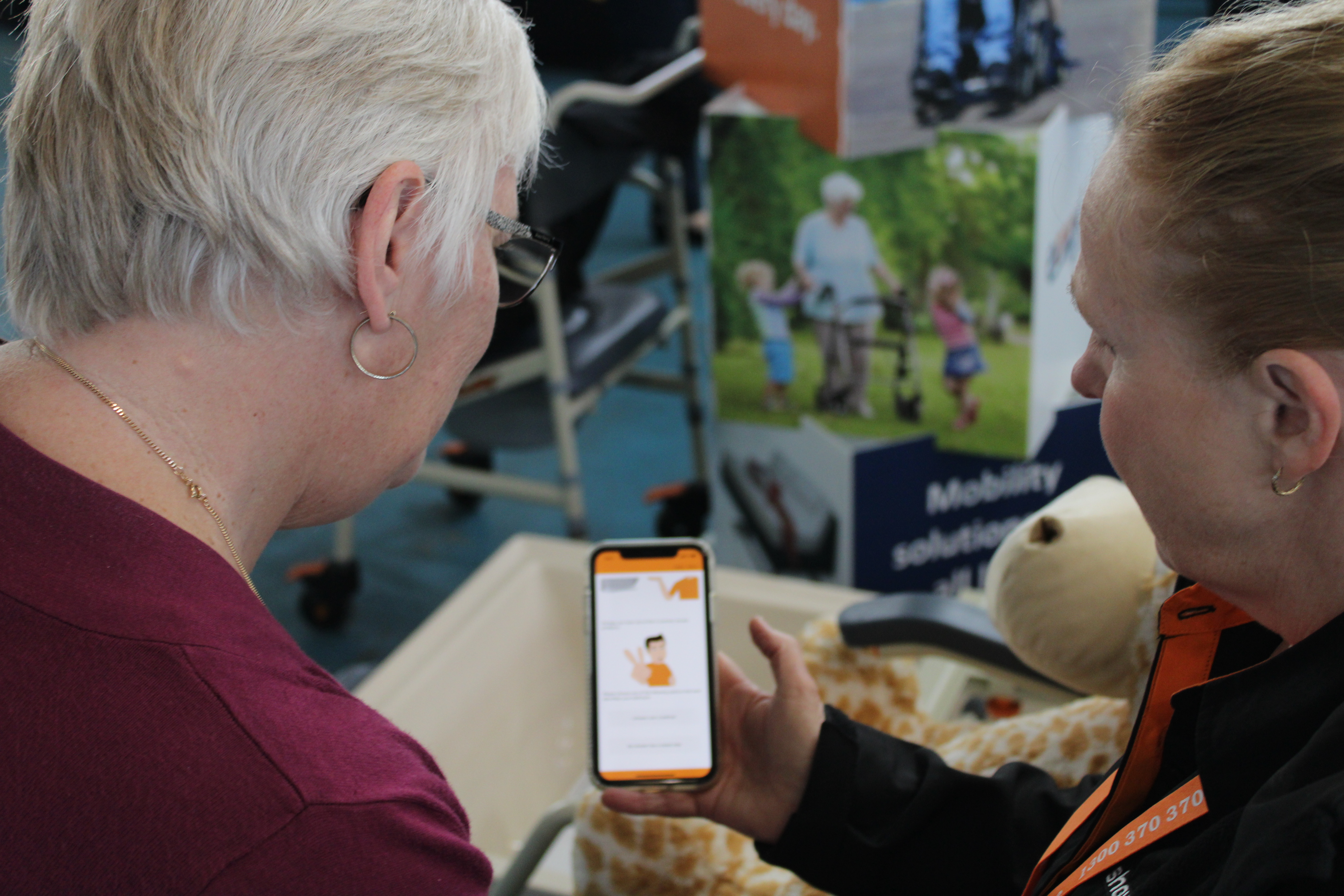 Two women look at an AT app and engage with each other.