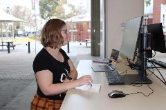 A lady uses a trackpad at a computer at the library.