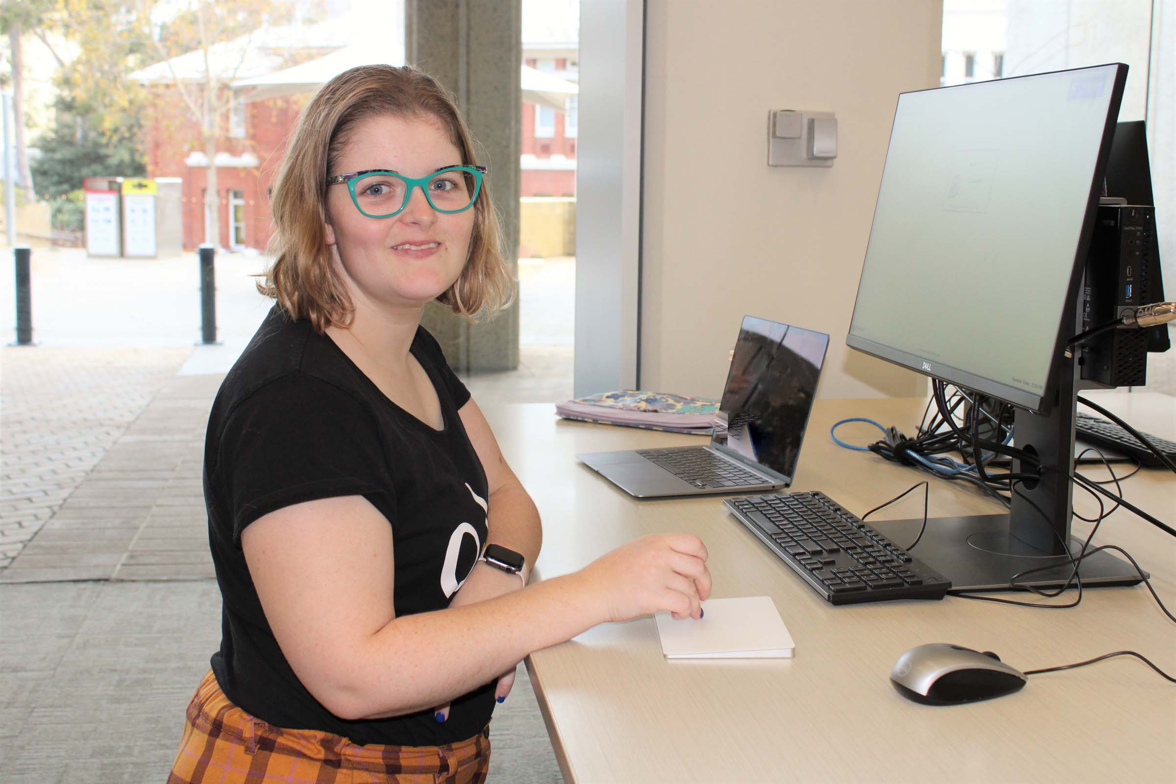 A lady works at her computer in the library and smiles. A lady works at her computer in the library and smiles.