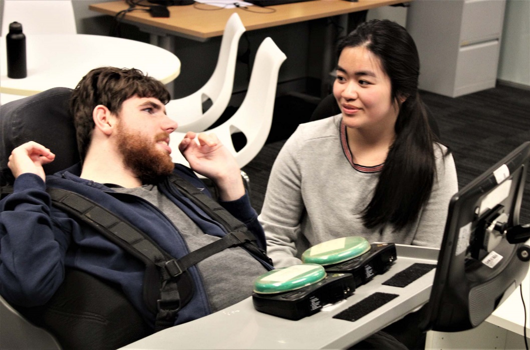 A man and a lady work together at an adapted work station.