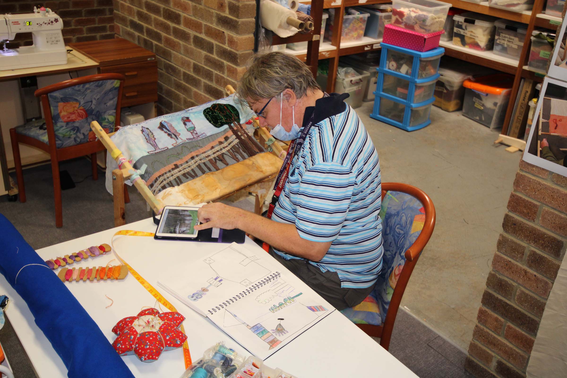 A man sits at a craft work station and works on his adaptive frame.