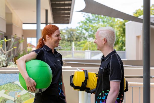 Two personal trainers hold exercise balls and smile at each other Two personal trainers hold exercise balls and smile at each other