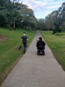 Nerine sits in her wheelchair with her son and walks the dog