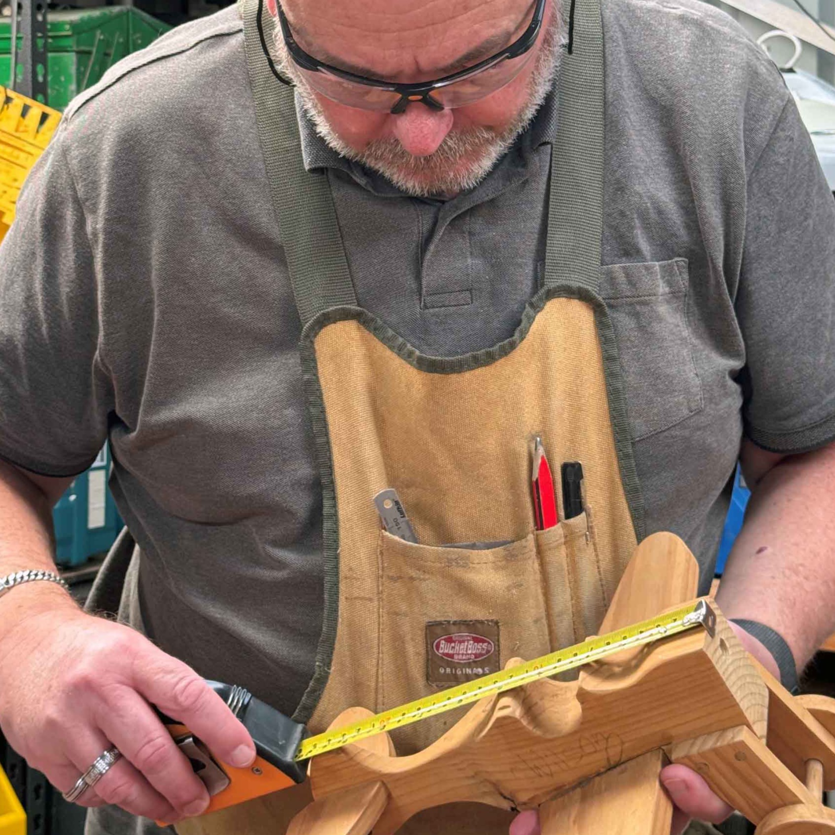Measuring up with low vision 2 A man standing in his workshop holds a children's toy as he measures it with a measuring talking measuring tape.
